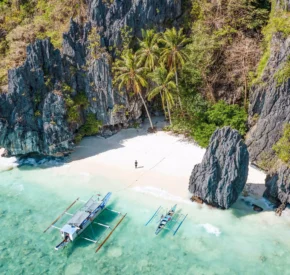 View from above of sandy beach and rock formations with clear water in Philiipines