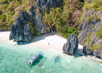 View from above of sandy beach and rock formations with clear water in Philiipines